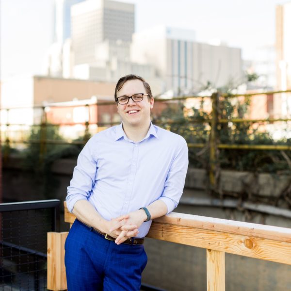 OCCC Alumni, Zach on a balcony in front of downtown OKC skyline